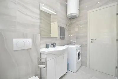 a white bathroom with a sink and a washing machine at Holiday Home Stanka in Kotor