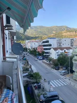 a woman standing on a balcony looking at a city street at Budva in Budva