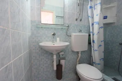 a bathroom with a sink and a toilet and a mirror at Apartman Ksjusa in Sutomore