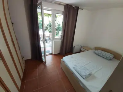 a small bedroom with a bed and a large window at Two Bedrooms Apartment With Garden View in Budva
