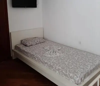 a bed with a gray and white comforter on it at Apartmani Monić in Ulcinj