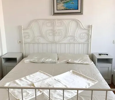 a white bed with a white headboard and two tables at Apartmani Monić in Ulcinj