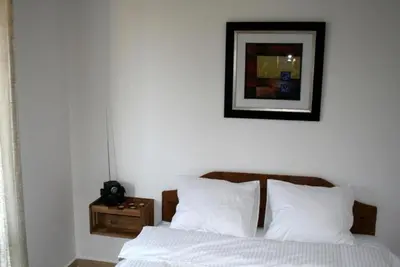 a bed with white sheets and a picture on the wall at Villa ALEA in Dobra Voda