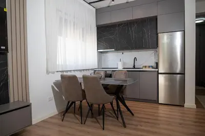a kitchen with a table and chairs and a refrigerator at Urban Coast - Ulcinj Apartment in Ulcinj