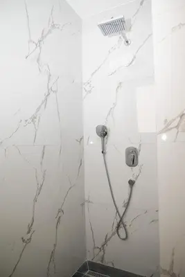a shower in a bathroom with white marble walls at Urban Coast - Ulcinj Apartment in Ulcinj