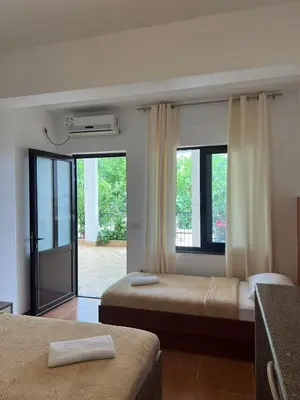 a room with two beds and a balcony with windows at Enes Apartments in Ulcinj