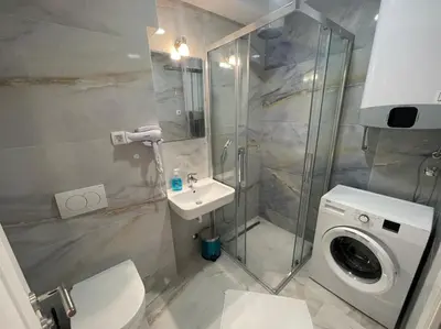 a bathroom with a shower toilet and a washing machine at Apartment ViSi 19 in Budva