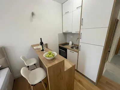 a small kitchen with white cabinets and a bowl of fruit on a counter at Apartment ViSi 19 in Budva