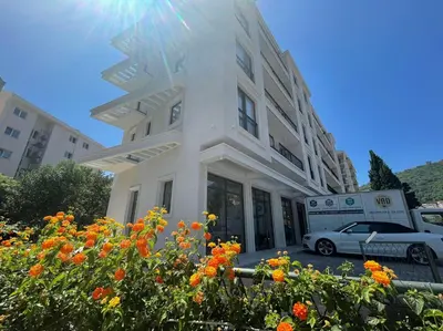 a white building with a car parked in front of it at Apartment ViSi 19 in Budva