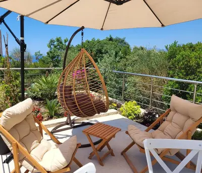 a patio with chairs and a swing and an umbrella at MiLA - Hladna Uvala in Utjeha