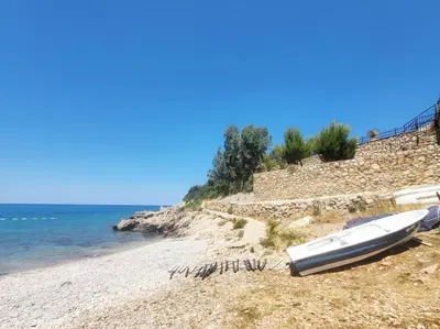 a boat sitting on a beach next to the water at MiLA - Hladna Uvala in Utjeha