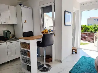 a kitchen with a counter and a table with a chair at MiLA - Hladna Uvala in Utjeha