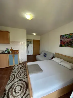 a bedroom with a large white bed and a kitchen at Apartman Buljarica-Bačvice 1 in Petrovac na Moru