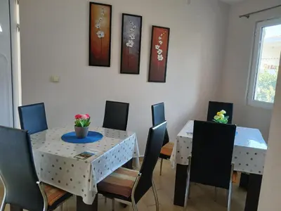 a dining room with a white table and chairs at Apartmani Bisser in Sutomore