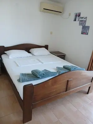 a bed with white sheets and blue towels on it at Apartmani Bisser in Sutomore