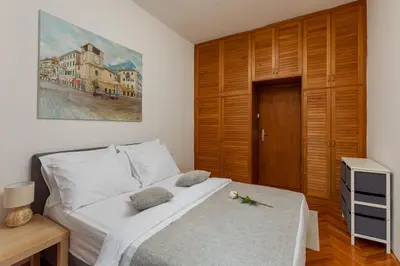 a bedroom with a white bed and a wooden door at Epoha Apartment in Kotor