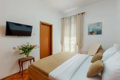 a bedroom with a bed and a tv on the wall at Epoha Apartment in Kotor