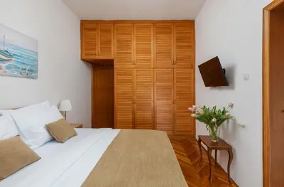 a bedroom with a white bed with a vase of flowers at Epoha Apartment in Kotor
