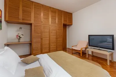 a bedroom with a bed and a tv and a chair at Epoha Apartment in Kotor