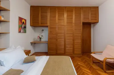 a bedroom with a bed and a chair and a closet at Epoha Apartment in Kotor