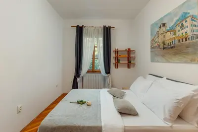 a white bed in a room with a window at Epoha Apartment in Kotor
