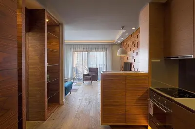 a kitchen with wooden cabinets and a living room at Modern home in the city center in Budva