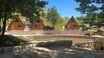 a group of three wooden huts with a stone wall at Gorska Dolina in Ivanova Korita