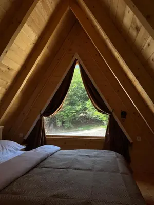 a bed in a attic with a window at Gorska Dolina in Ivanova Korita