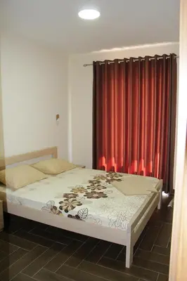 a bedroom with a bed with a red curtain at Apartments Family Ibrahimi in Ulcinj