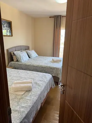 two beds in a room with a door open at Apartments Family Ibrahimi in Ulcinj