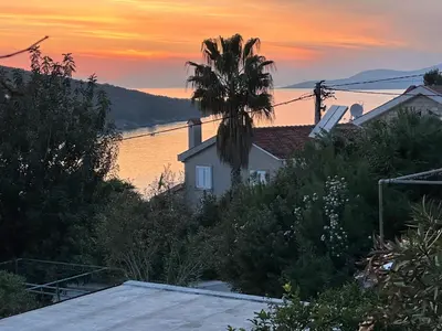 a palm tree in front of a house with a sunset at Kalina in Bigovo