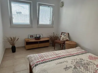 a bedroom with a bed and a desk and two windows at Kalina in Bigovo