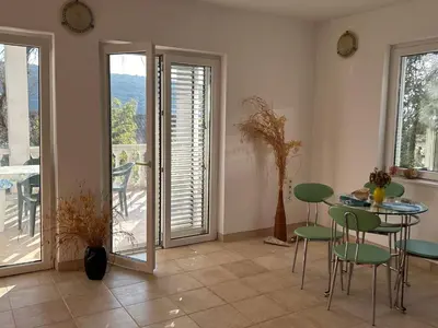a living room with a table and chairs and a balcony at Kalina in Bigovo
