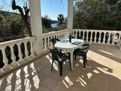 a white table and chairs on a porch with a fence at Kalina in Bigovo
