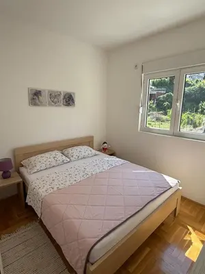 a bedroom with a bed and a window at Cozy Apartment with Private Garage - Walk to City Center in Budva