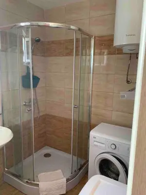 a shower in a bathroom with a washing machine at Cozy Apartment with Private Garage - Walk to City Center in Budva