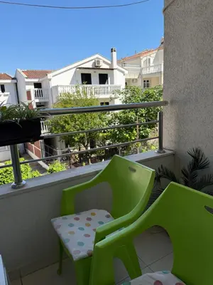a green chair sitting on the balcony of a apartment at Cozy Apartment with Private Garage - Walk to City Center in Budva