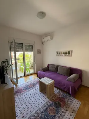 a living room with a purple couch and a table at Cozy Apartment with Private Garage - Walk to City Center in Budva