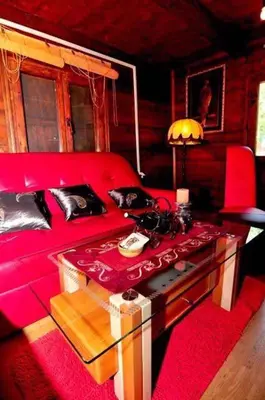 a living room with a red couch and a table at Vikendica na obali rijeke Bojane sa velikim dvoristem, parkingom ljetnjom kuhinjom i mjestom za rostilj in Ulcinj