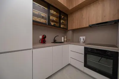 a kitchen with white cabinets and a black oven at Apartment Ejna in Dobra Voda