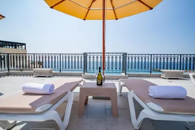 a patio with two lounge chairs and an umbrella at Apartment Ejna in Dobra Voda