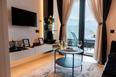 a living room with a table and a large window at Apartman Katica in Becici