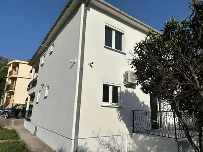 a white building with a balcony on the side of it at Apartmani Aki 6 in Sutomore