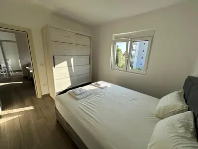 a bedroom with a large white bed with a window at Apartmani Aki 5 in Bar