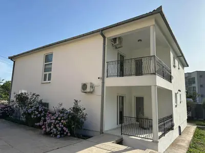 a white building with a balcony and some flowers at Apartmani Aki 5 in Bar