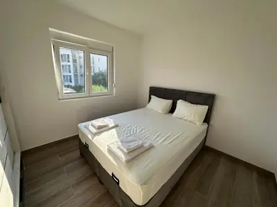 a small bedroom with a bed with a window at Apartmani Aki 5 in Bar