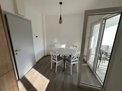 a dining room with a table and chairs and a balcony at Apartmani Aki 5 in Bar