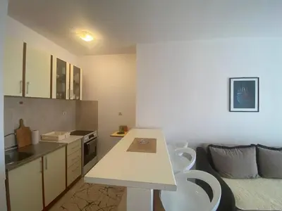 a kitchen with two white chairs and a table at Peaceful Apartment with a Sea View, in Becici in Becici