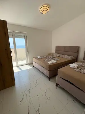 a bedroom with two beds and a large window at Apartmani Kula in Pečurice