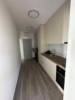 a kitchen with white cabinets and a wooden floor at Apartmani Aki 4 in Bar